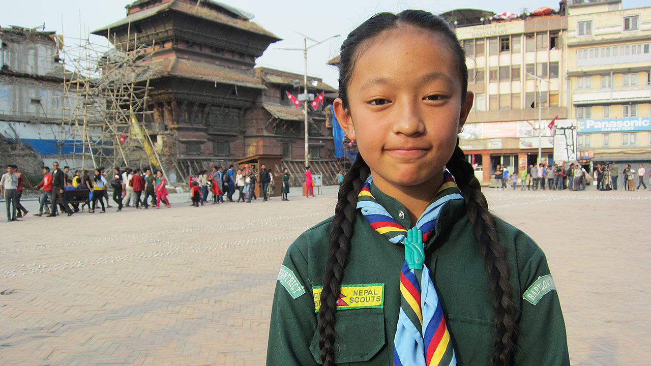 Hymyilevä nepalilainen partiolaistyttö torilla Kathmandussa