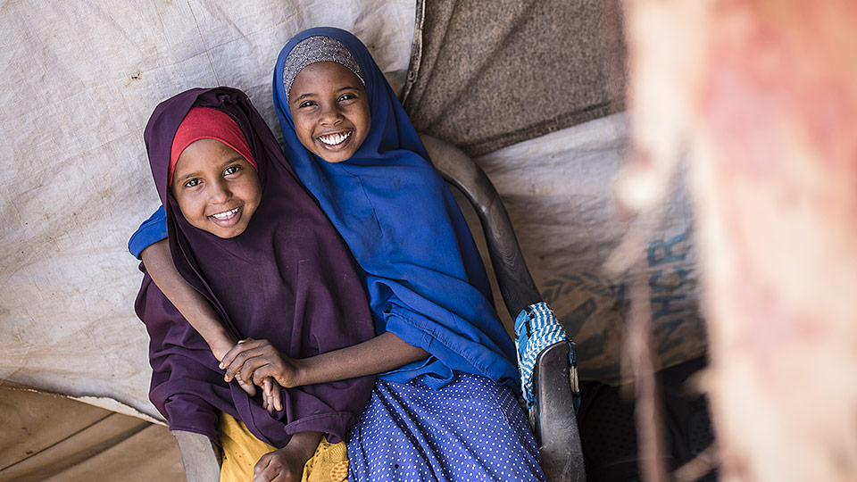 Hymyilevät sisarukset Bisfara ja Fatouma kotonaan yksinkertaisssa majassa